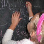 Emerson adds her art to our chalkboard wall.