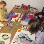 Youth Artists Evelyn, Sofia and Hannah working with acrylic paint on canvas board.